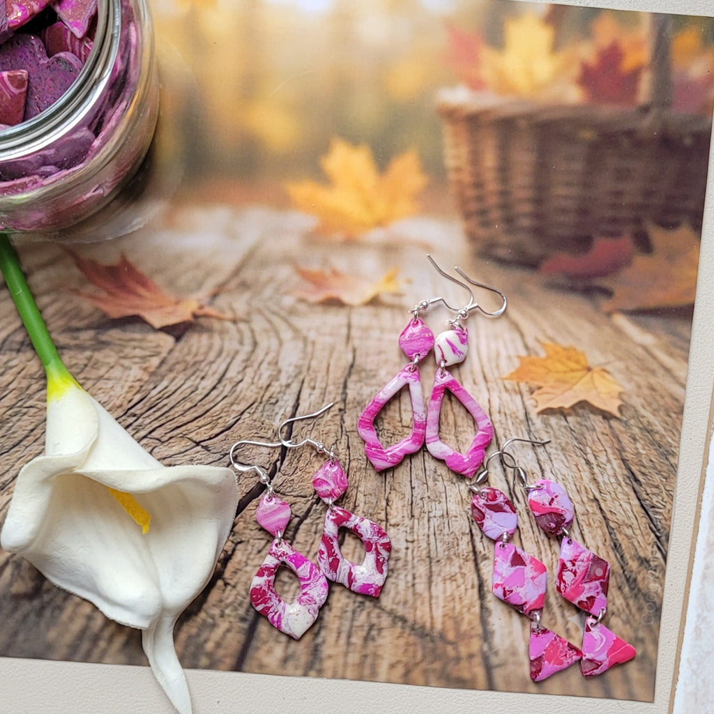 Les trois modèles de boucles d’oreilles Rétro-chic aux motifs roses, blancs et bordeaux, présentés près d’un arum blanc sur un décor boisé -Alysel Créations